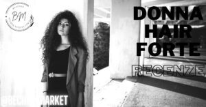 a woman with voluminous curly hair posing indoors near a "Market" sign, promoting Donna Hair Forte product reviews.