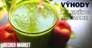 a glass of green barley (zelený ječmen) drink with a straw, surrounded by fresh apples and greens