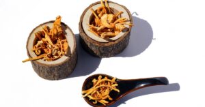 dried Cordyceps sinensis pieces stored in carved wooden containers and a wooden spoon