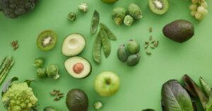 a vibrant assortment of alkaline-rich foods including kiwi, avocado, green apple, broccoli, Brussels sprouts, snap peas, grapes, and chia seeds.