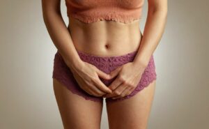 a person holding lower abdomen area, illustrating potential discomfort related to cystitida