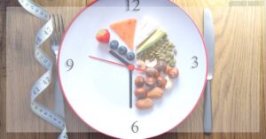 a clock illustrating a healthy fasting schedule with a plate of strawberries, nuts, seeds, and watermelon, alongside a measuring tape.